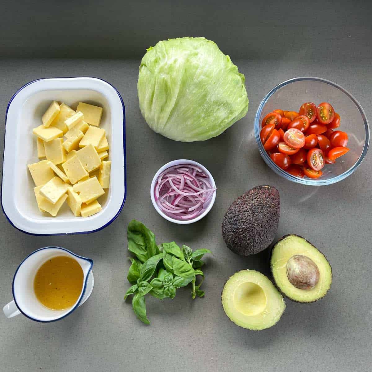 The ingredients for haloumi and avocado salad on a grey bench.