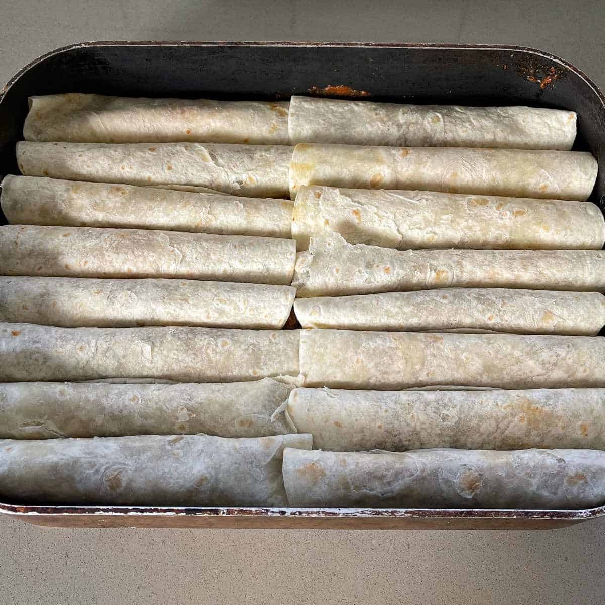 Beef enchiladas being prepared in a large tray
