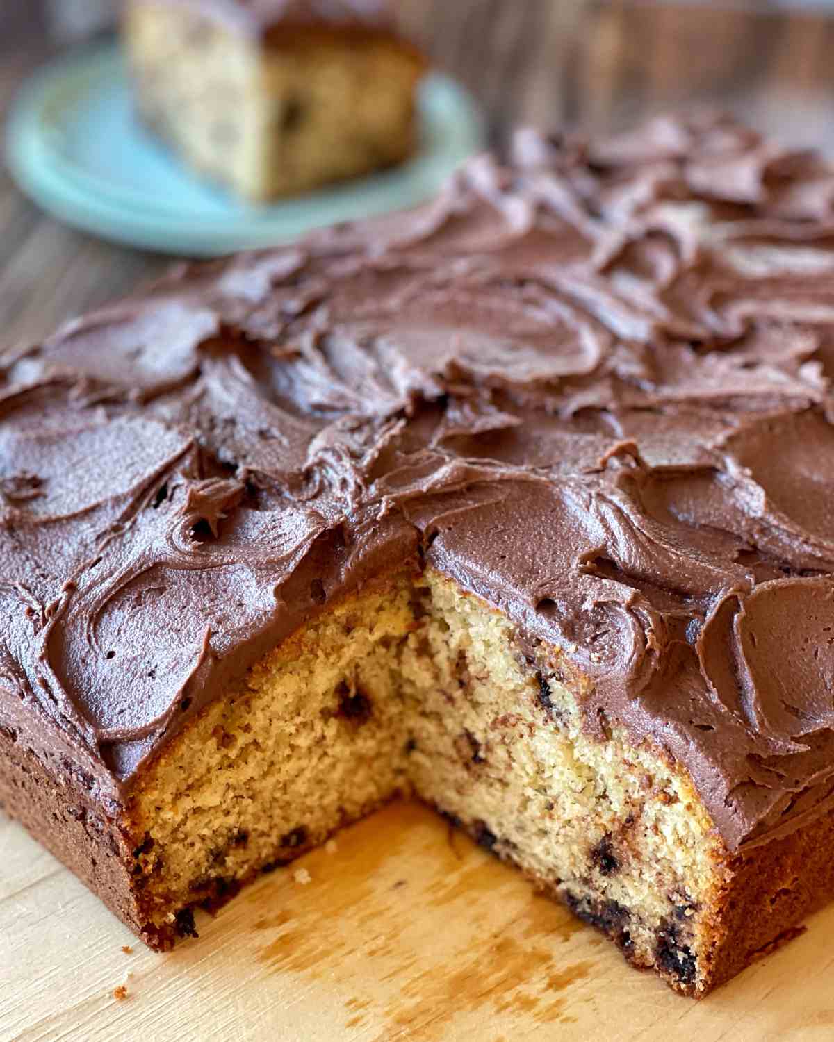 Iced banana chocolate chip cake with one portion removed.