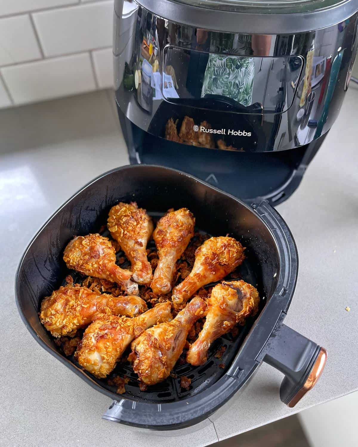 Cooked Crispy Chicken Drumsticks in the base of an air fryer.