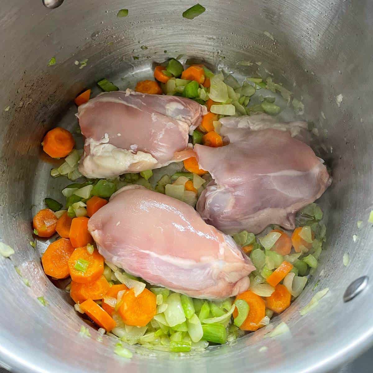 Onion, celery, carrot and chicken cooking in a large pot.