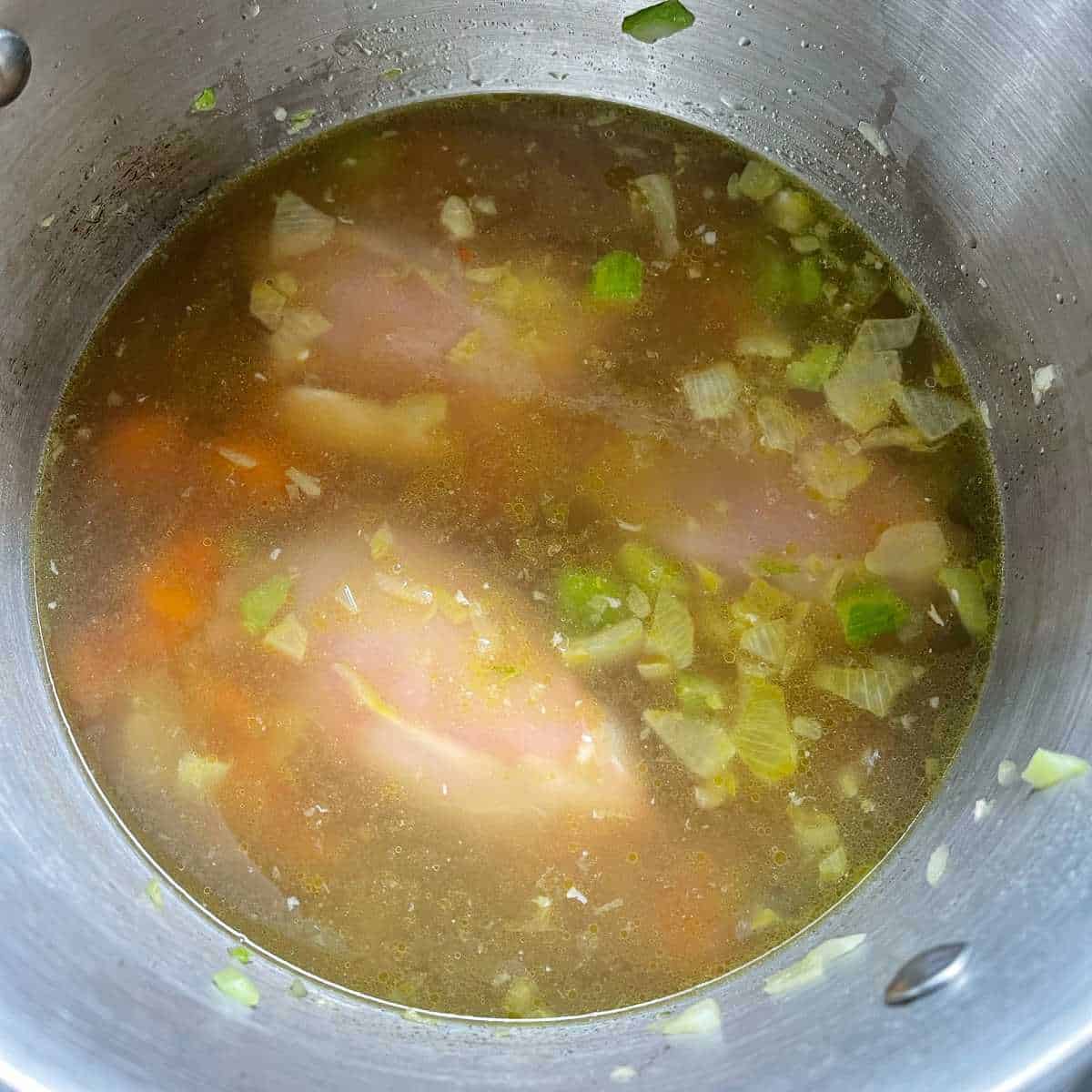 Stock, chicken and vegetables in a large pot.