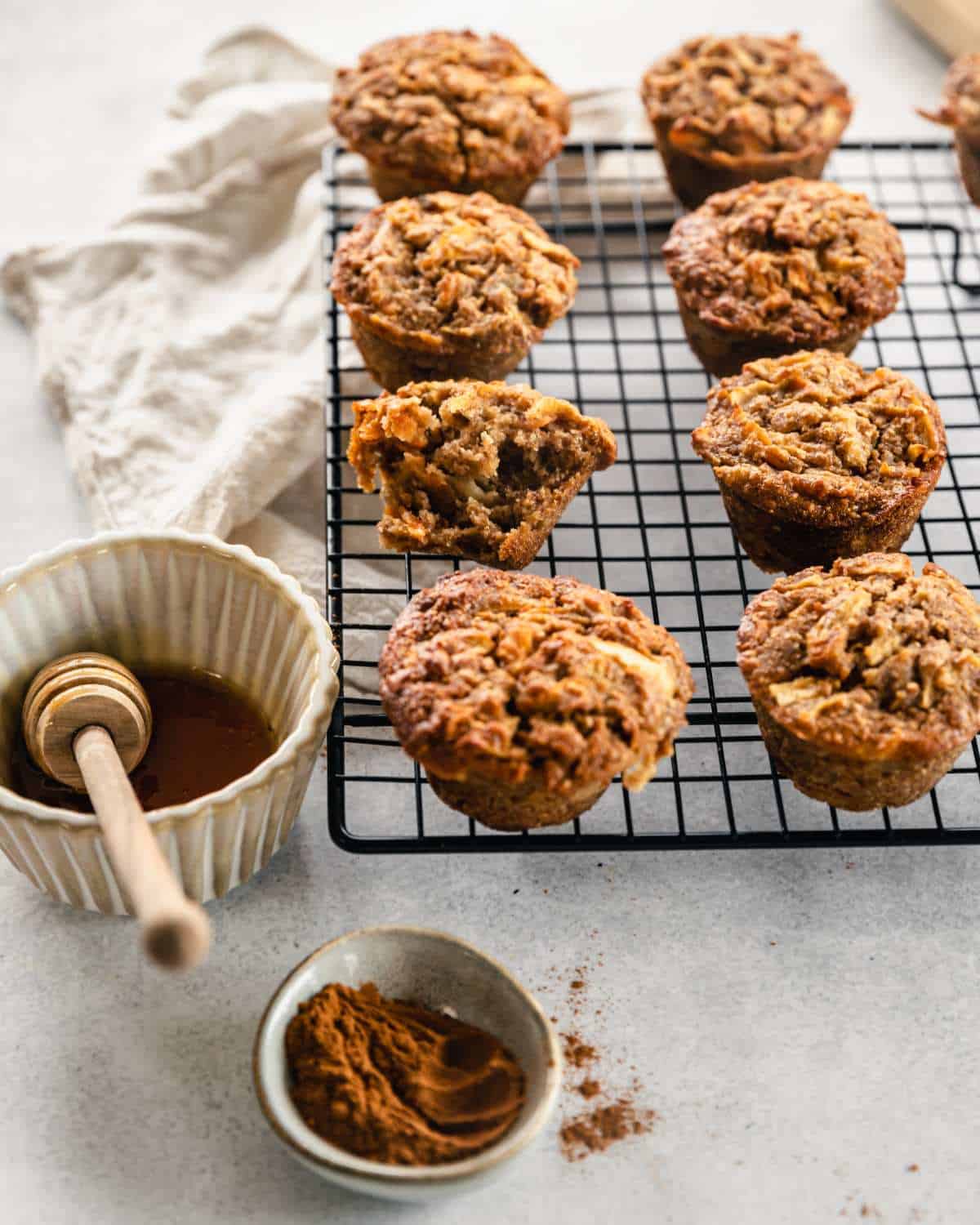 Cooked ABC Muffins cooling on a cooling rack. One muffin has been broken open to show the cooked filling.