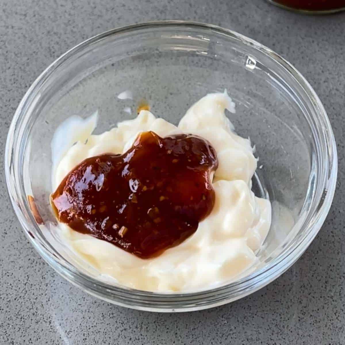 A small glass bowl with mayonnaise and Whitlock & Sons Texas BBQ Style Marinade to make BBQ sauce.