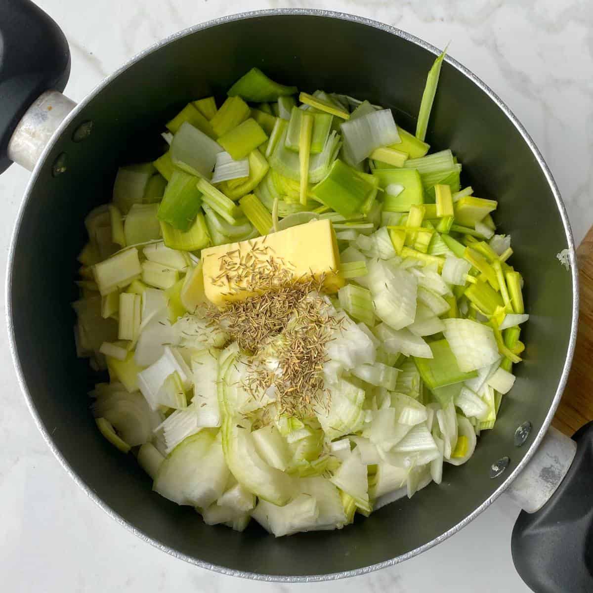 Sliced onion, celery and leak with butter and herbs in a large pot before being reduced down to make a stock.