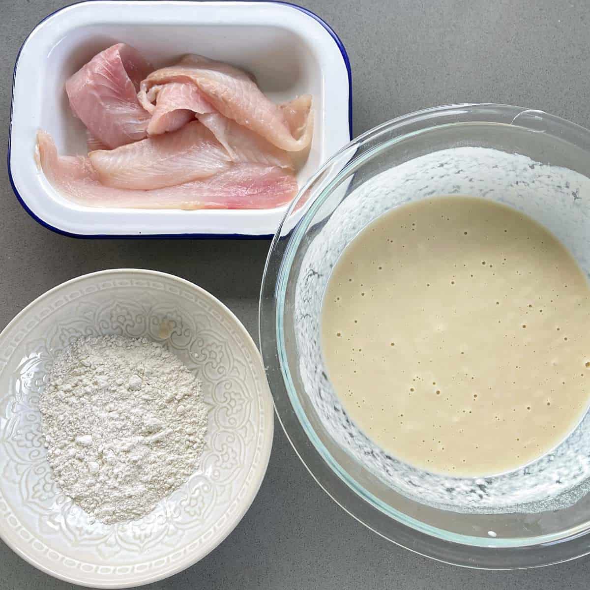 A birds eye view of flour, batter and fish demonstrating the process of how to batter the fish for the battered fish burgers.
