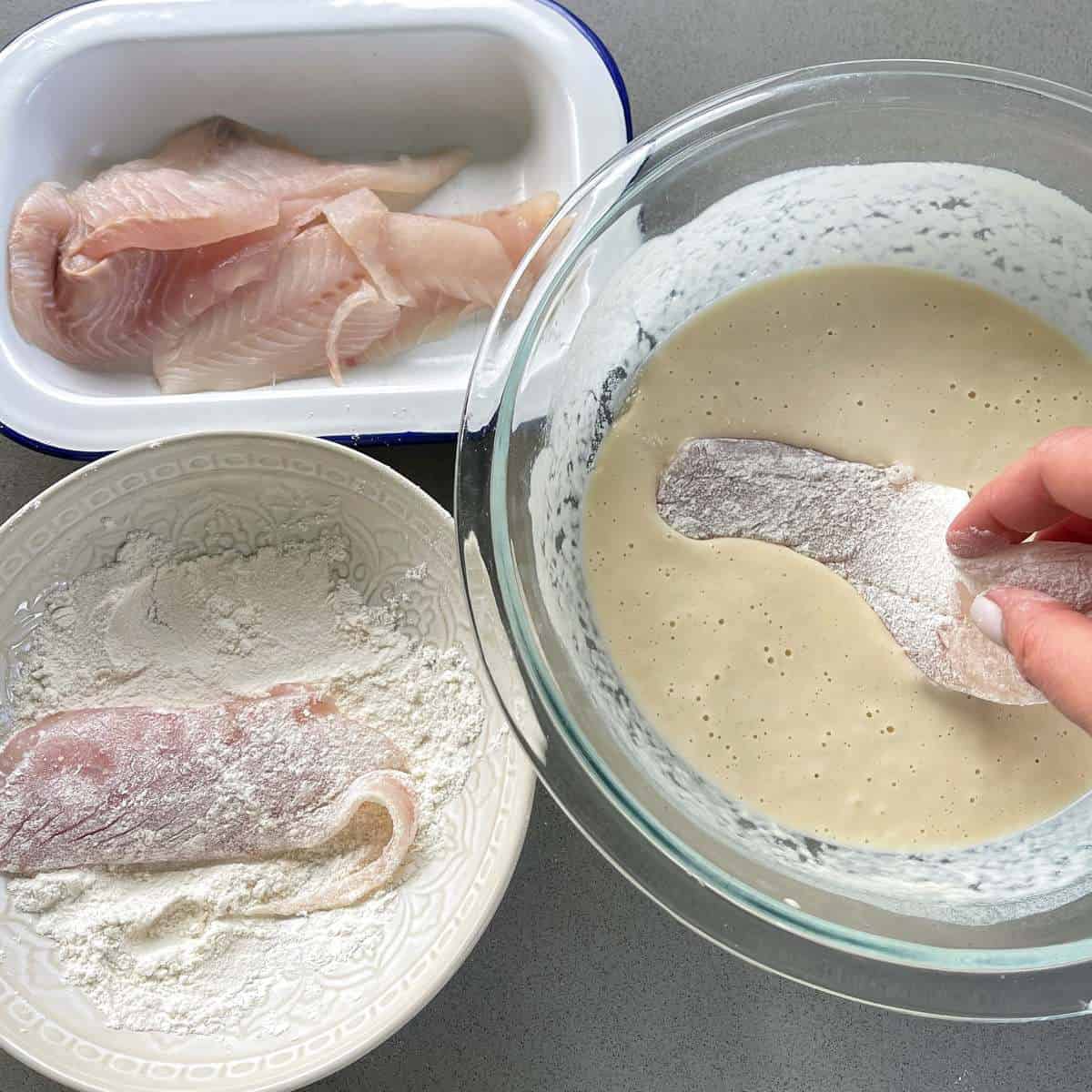 Showing the process of battering the fish for the battered fish burgers. One bowl of flour, one bowl of batter and one dish of fish.