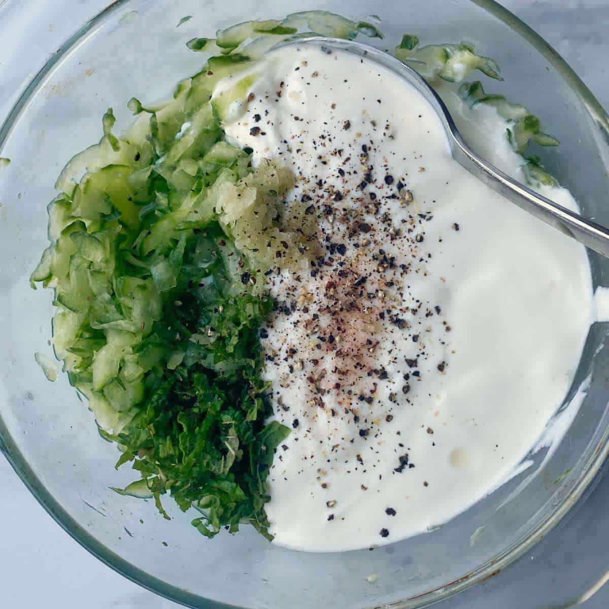 All if the ingredients for Tzatziki sauce in a small dish before being combined together.