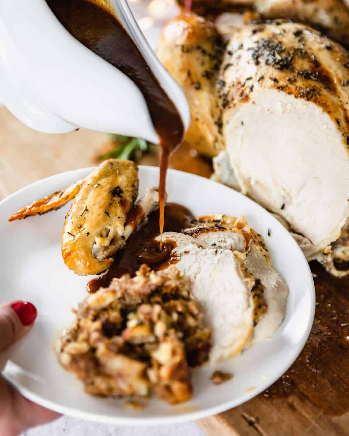 A white plate with a portion of Classic Roast Chicken with gravy being poured on top.