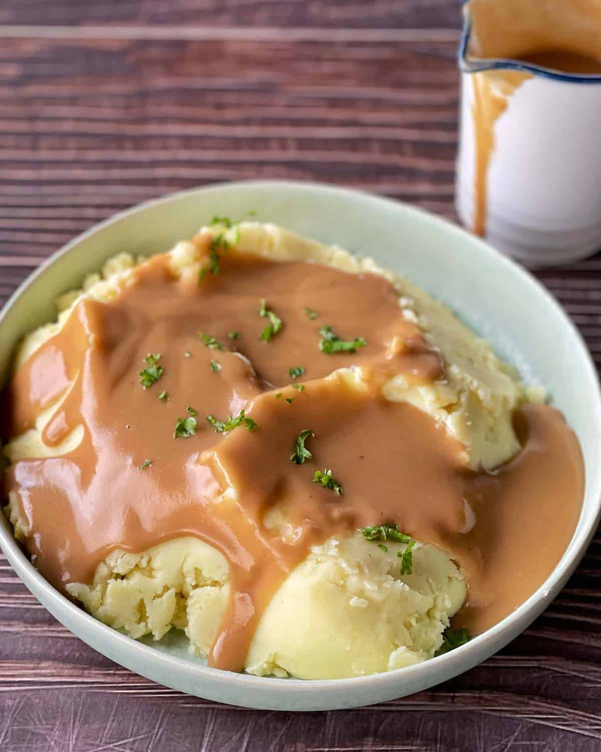 Potato and Gravy served in a white serving bowl with a few sprinkles of parsley on top.