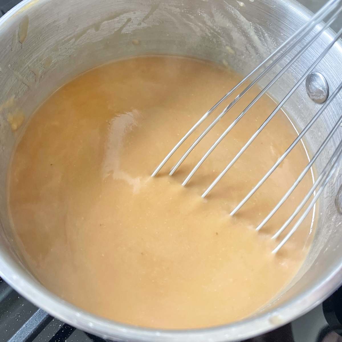 Gravy being stirred over a low heat in a small pot