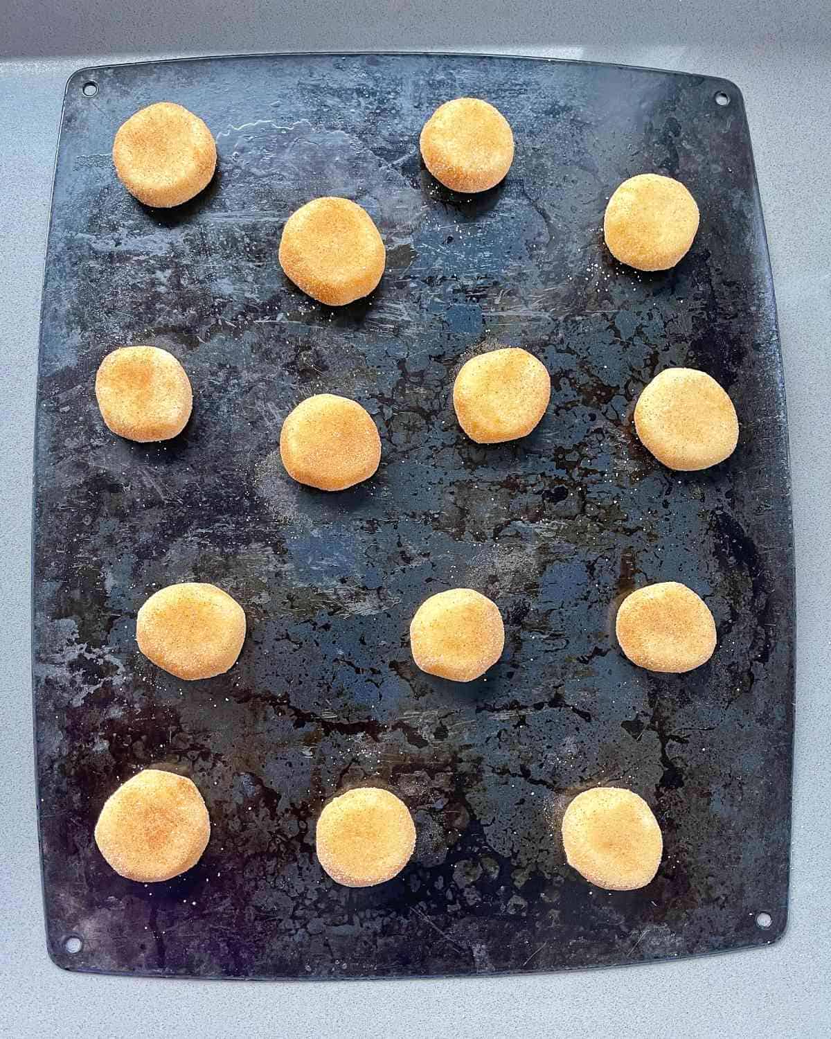 Flattened cookies on a baking tray.