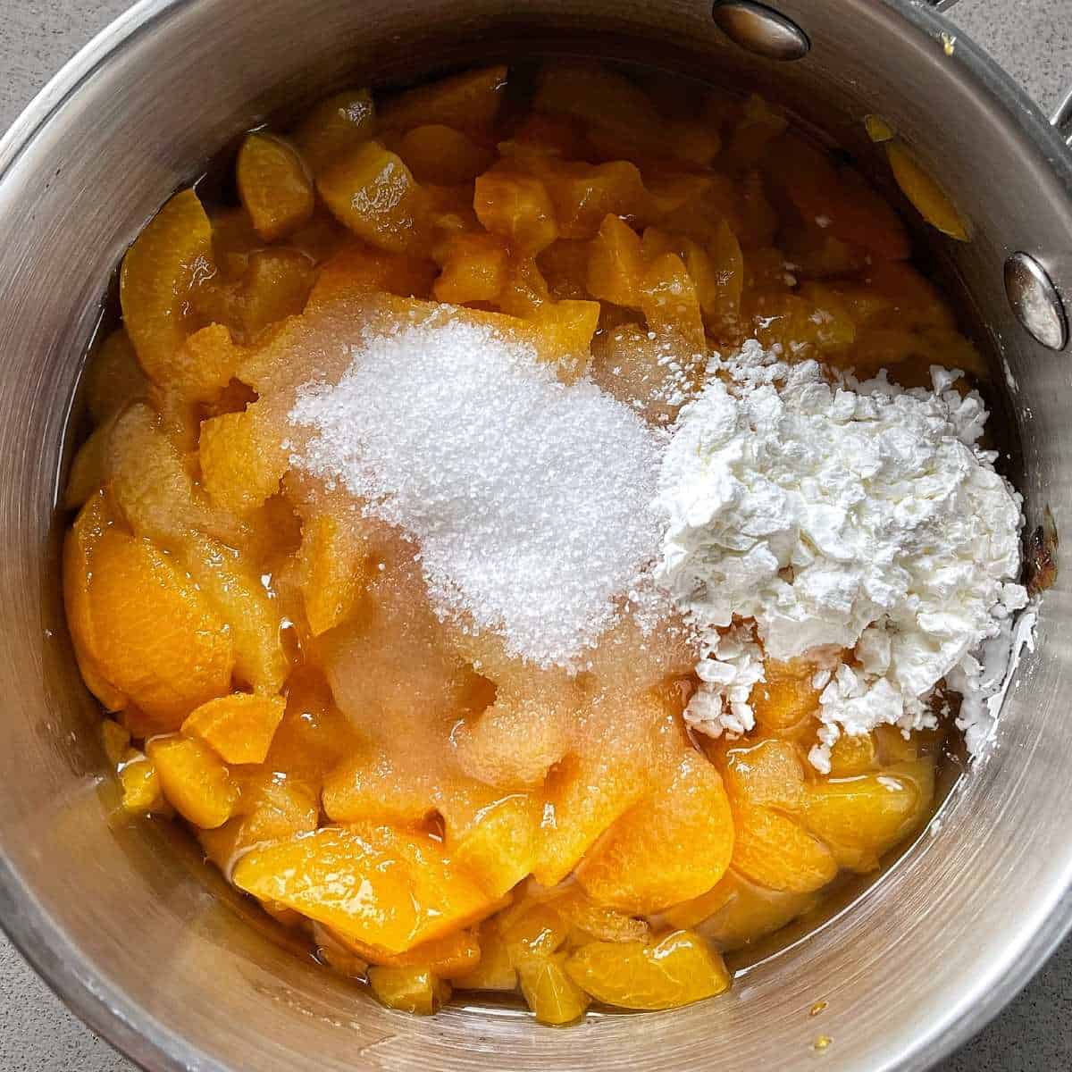 Sugar, corn flour and apricots simmering in a small pot