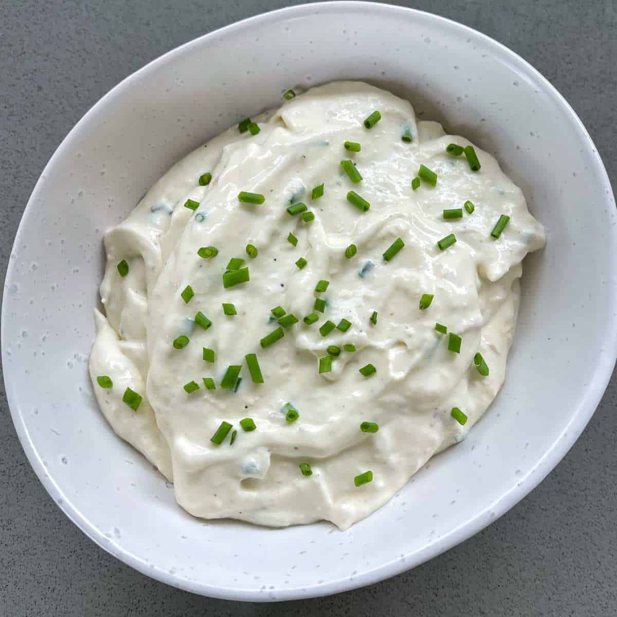 Creamed horseradish in a small white dish with chives on the top to garnish