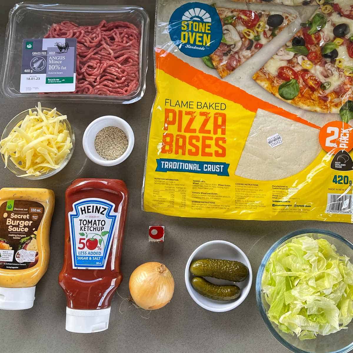 The ingredients for Big Mac Pizza on a grey bench top