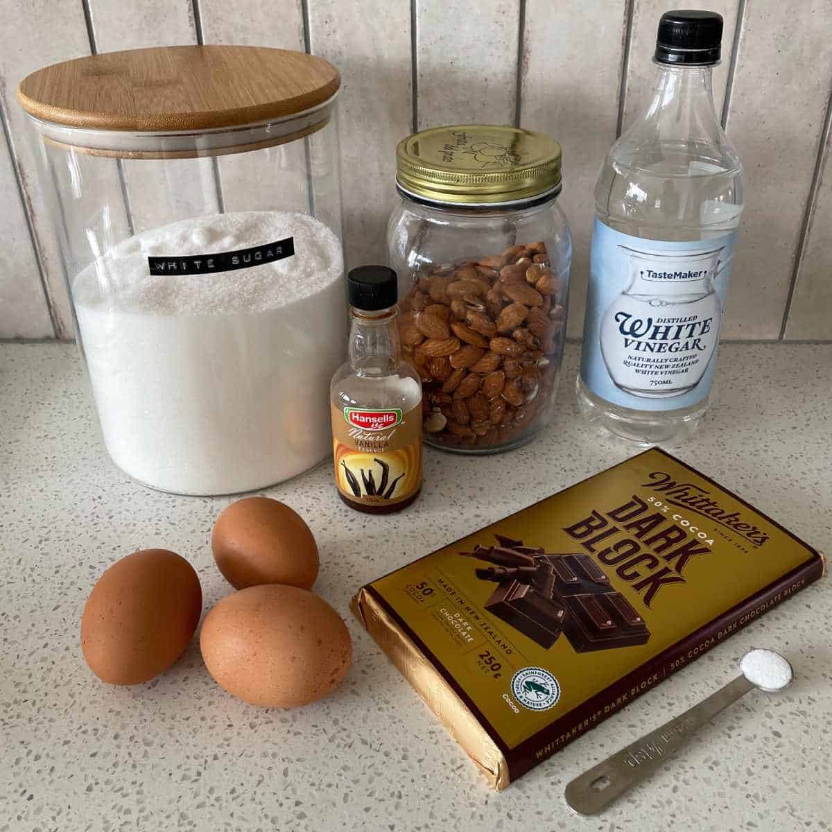 The ingredients to make Chocolate Almond Meringue Cookies on a marble bench top.