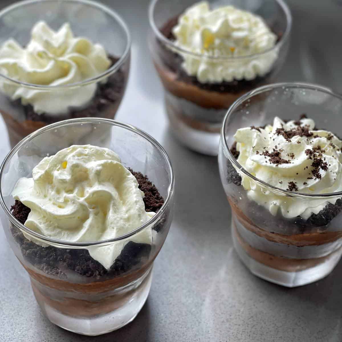 Four Coffee Chocolate Parfaits assembled with whipped cream on top about to be served.