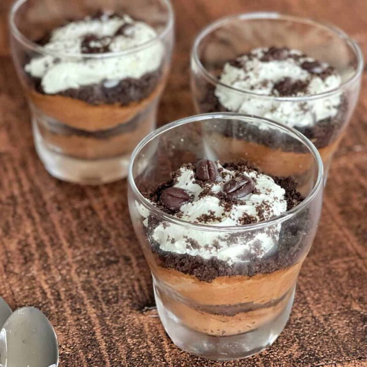 Three individual Coffee Chocolate Parfait's on a wooden chopping board.