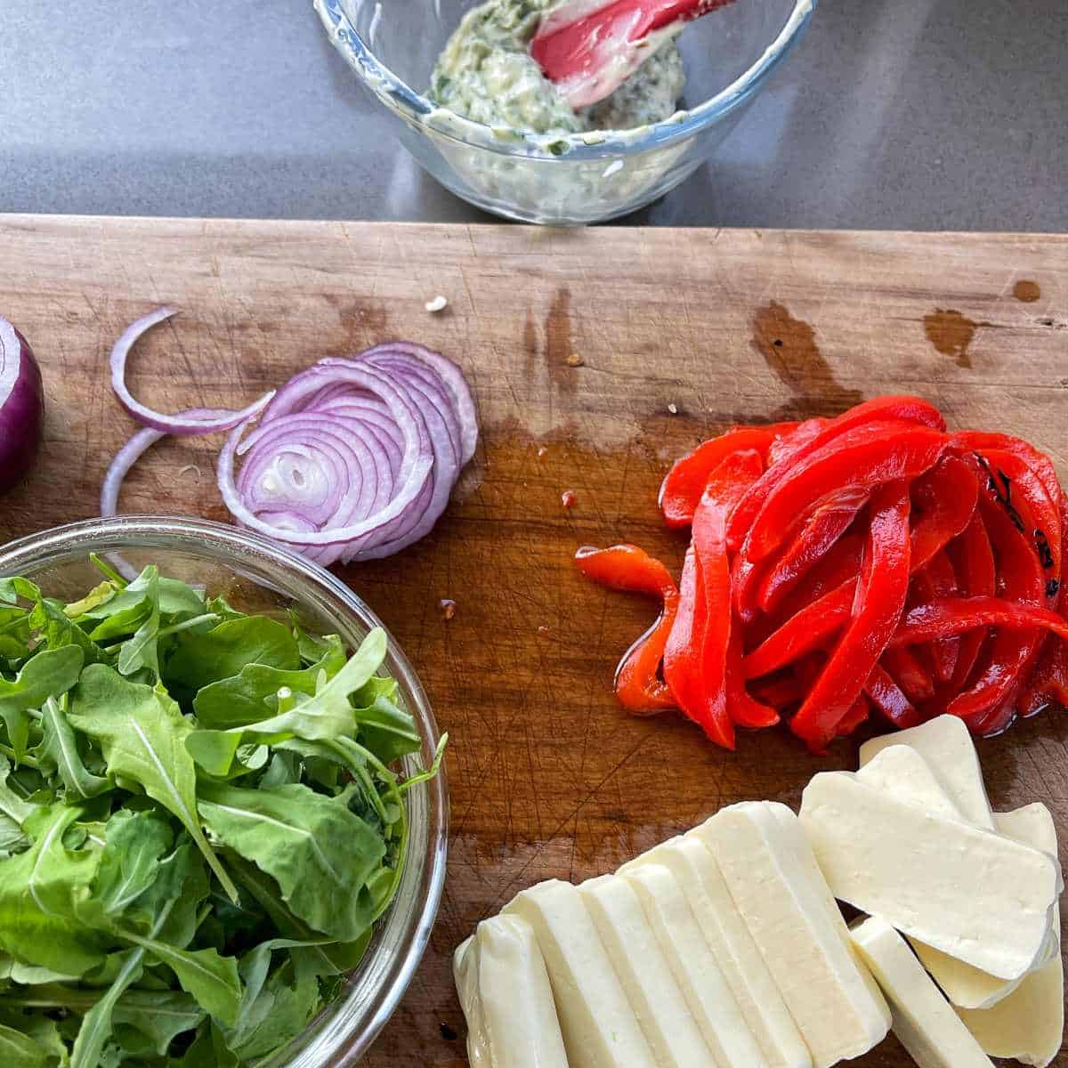 The sliced ingredients for a Halloumi Burger on a wooden chopping board.