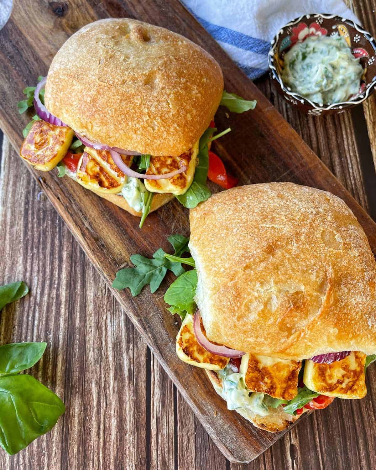 Two Halloumi Burger's on a wooden chopping board.