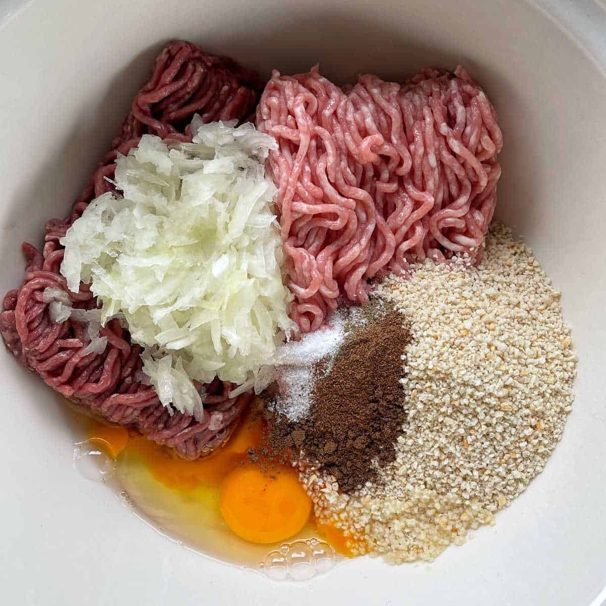 The ingredients to make the meatballs in a bowl before being mixed together.