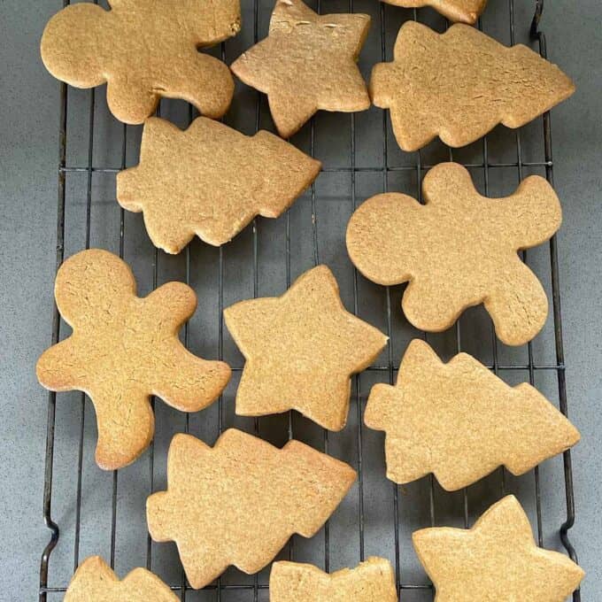 Cooked gingerbread cookie shapes cooling on a wired baking rack.