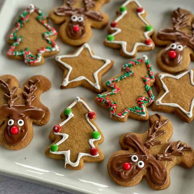 The iced and decorated gingerbread Christmas cookies served on a white platter square plate on a marble bench top.