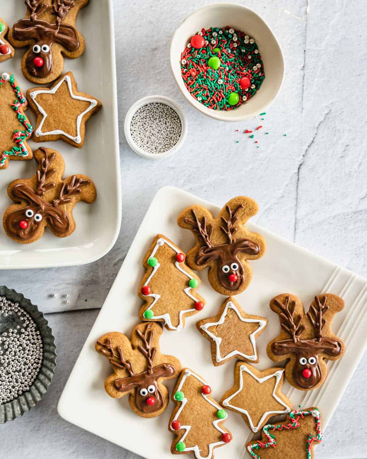 The iced and decorated gingerbread Christmas cookies served on a white platter square plate on a marble bench top.