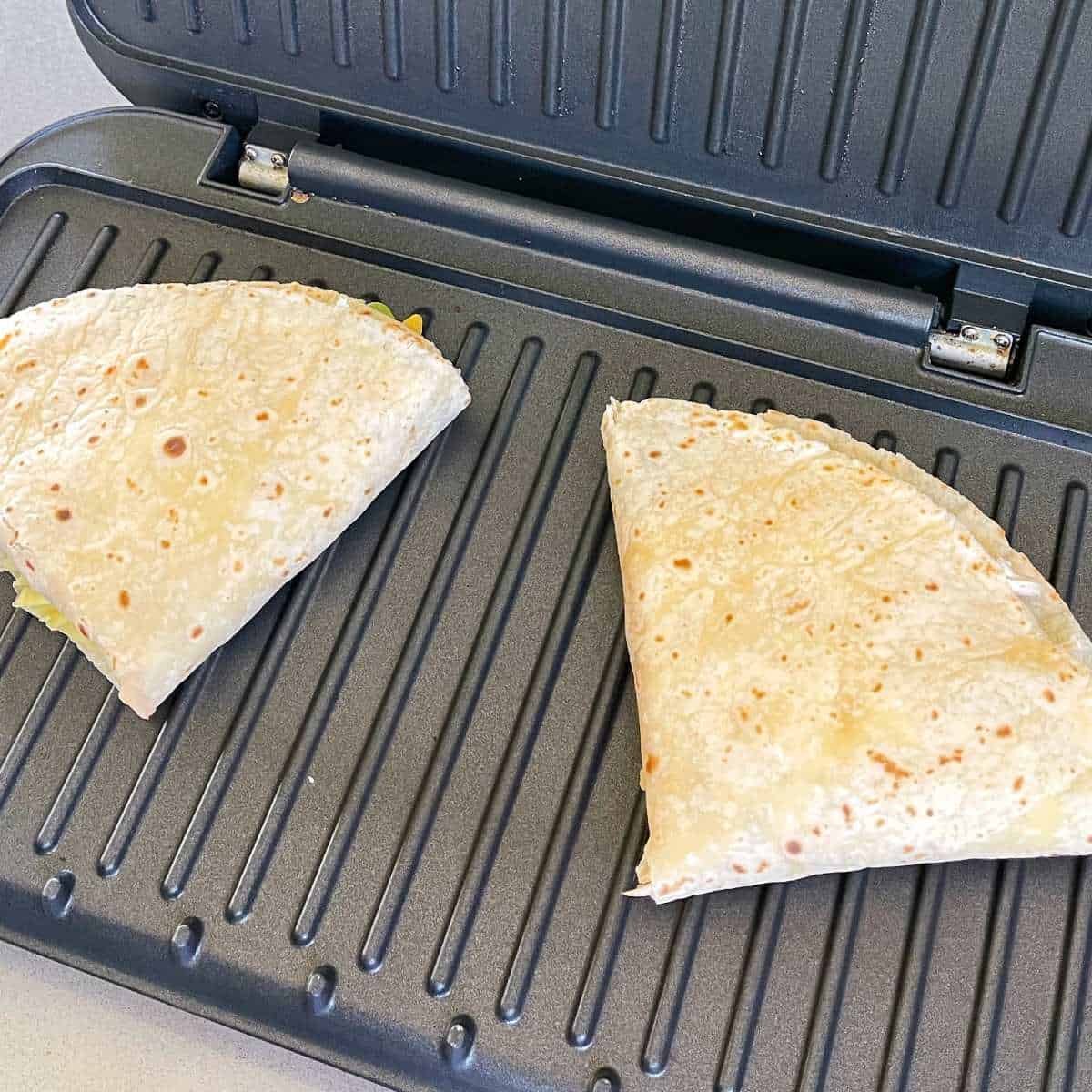 Two Chicken Tortillas toasting on a toasted sandwich maker
