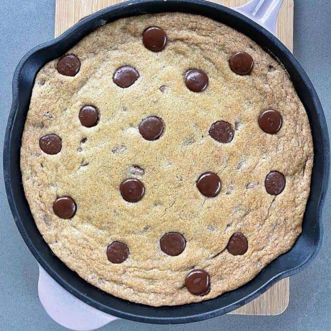 Cooked Chocolate Chip Skillet Cookie resting on a wooden chopping board.