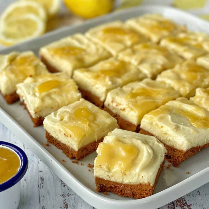 The set and sliced no bake lemon curd cheese cake served on a white platter with individual portions cut evenly.