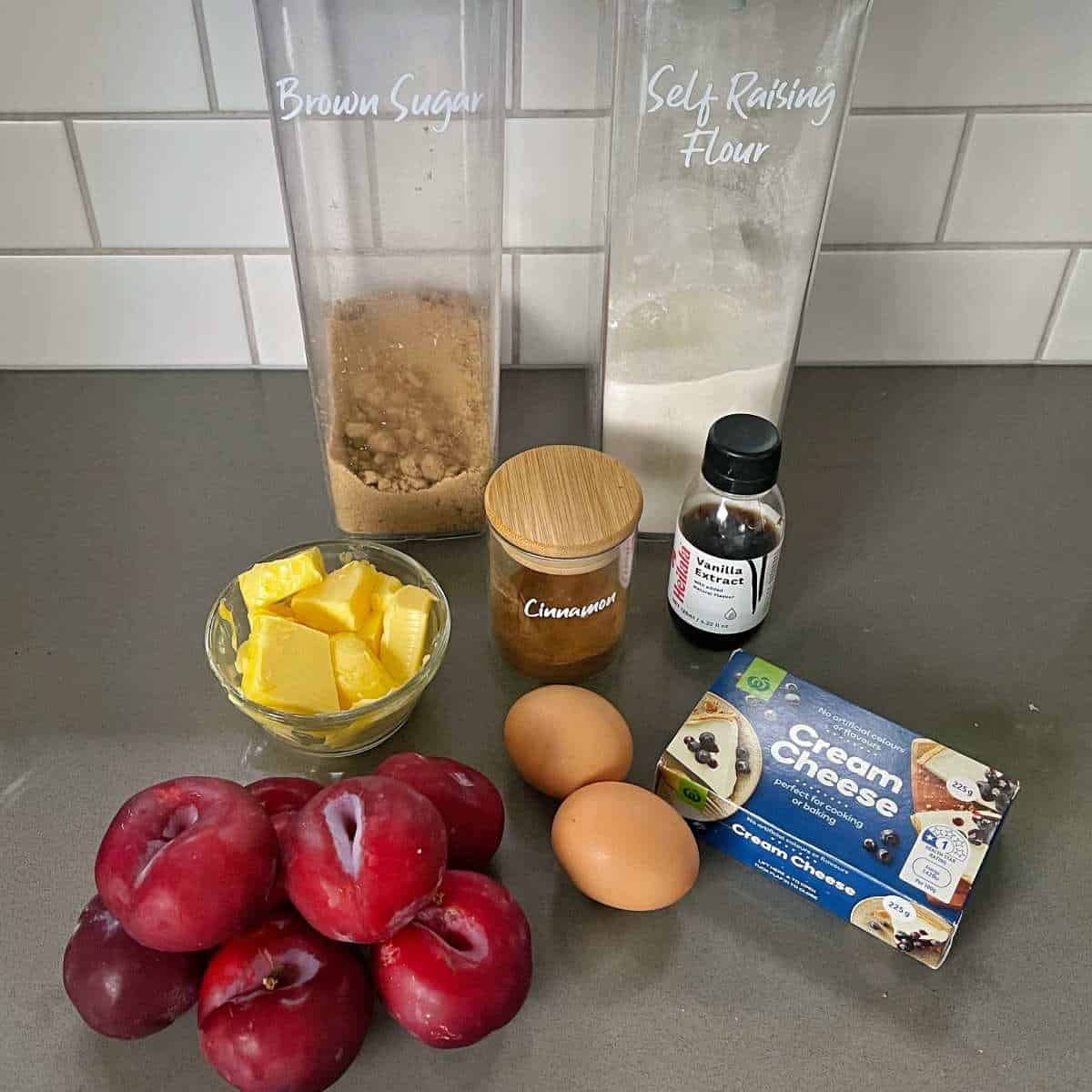 The ingredients to make plum and cream cheese tray bake on a grey bench top.