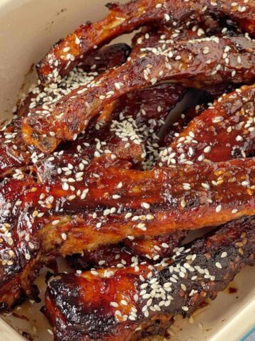 A close up of cooked pork ribs in a serving dish