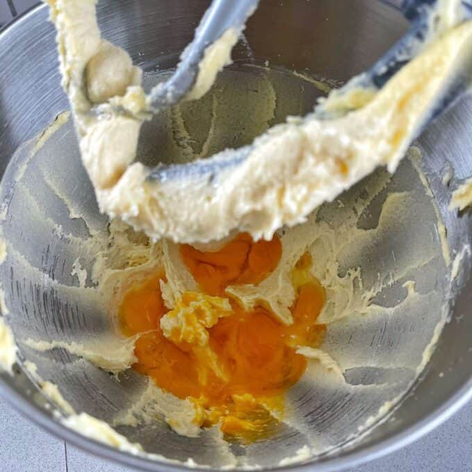 Eggs added to the creamed butter and sugar mixture in a mixing bowl for classic vanilla cupcakes.