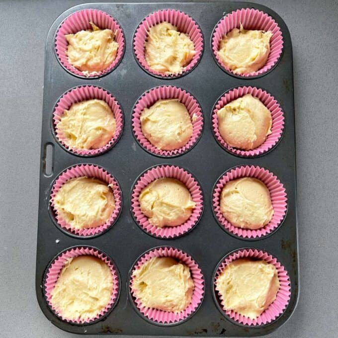A muffin tray filled with the cupcakes before being cooked in the oven.
