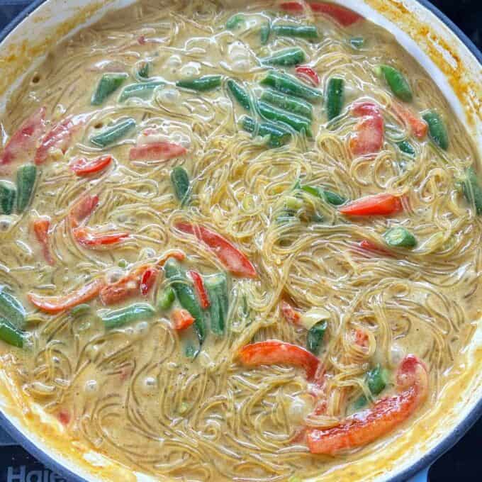 Yellow Fish Curry with Rice Noodle Curry cooking on a stovetop.