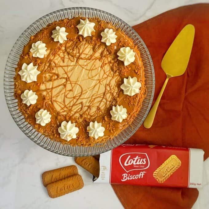 A birds eye view of the set Biscoff Cheesecake on a glass cake stand in a marble bench top