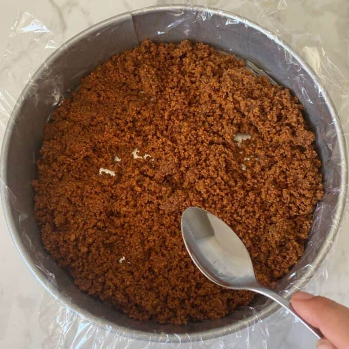 The crumb mixture being pressed into a line cake tin for the Biscoff Cheesecake.