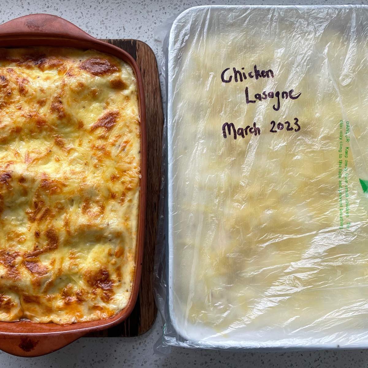 Two Chicken Lasagne on a marble bench. One has been cooked through and the other will be set aside to be frozen.