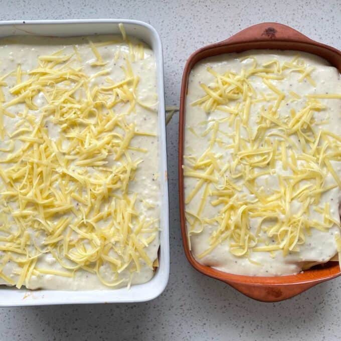 Two uncooked assembled Chicken Lasagne on a marble bench top.