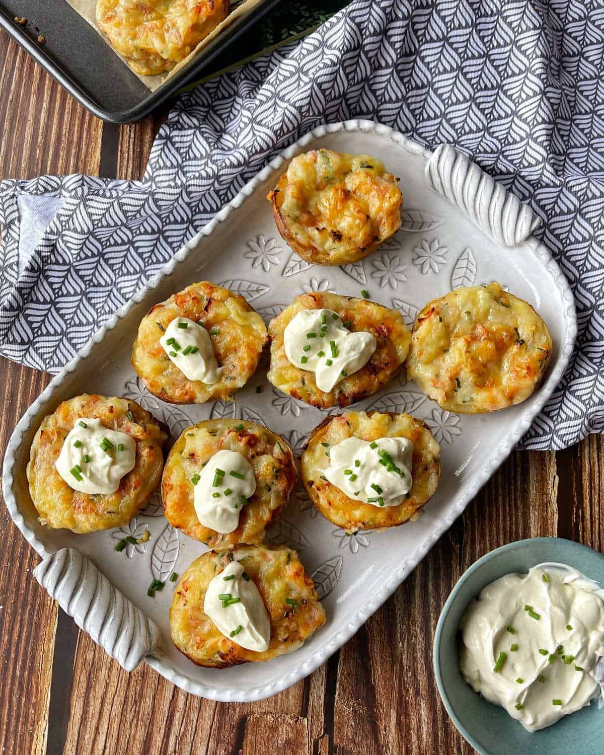 Jacket Potatoes served on a white platter with a dollop of sour cream and chives.