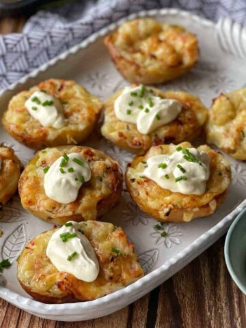 Jacket Potatoes served on a white platter with a dollop of sour cream and chives.