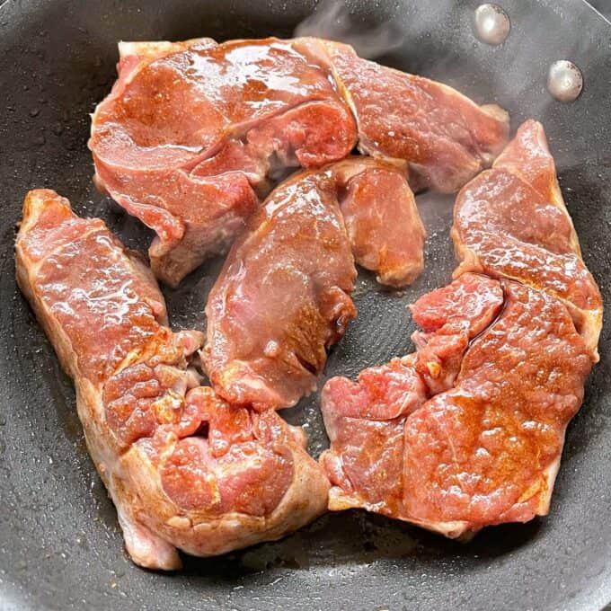 The marinated lamb frying in a fry pan.