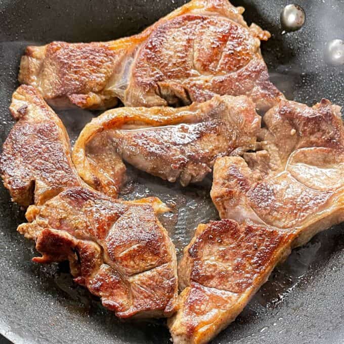 The marinated lamb frying in a fry pan.