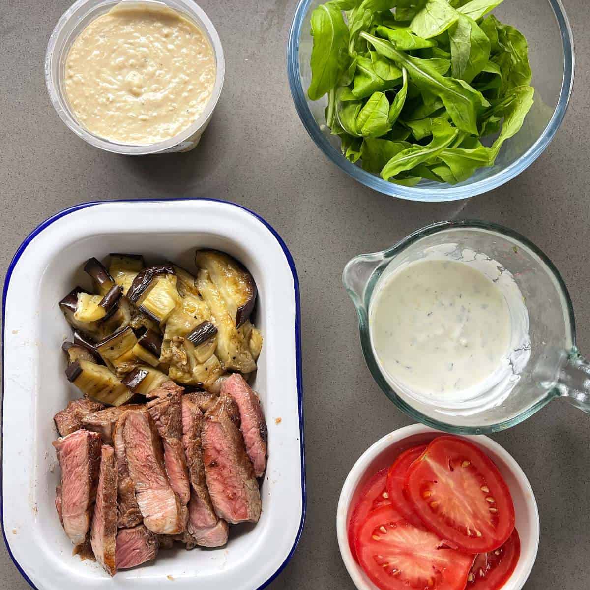 All of the sliced and cooked components for the Lamb and Eggplant burgers on a grey bench top.