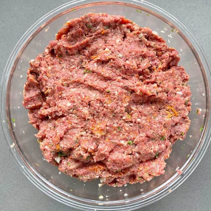 The combined meat mixture for the Meatloaf in a glass bowl.