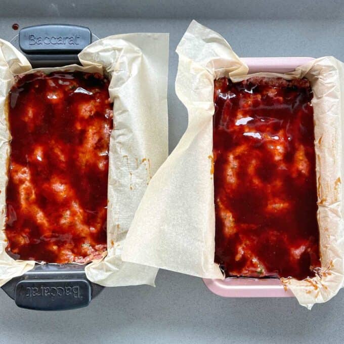 Two lined loaf tins with the meat pressed into them and the sauce poured on to the top.
