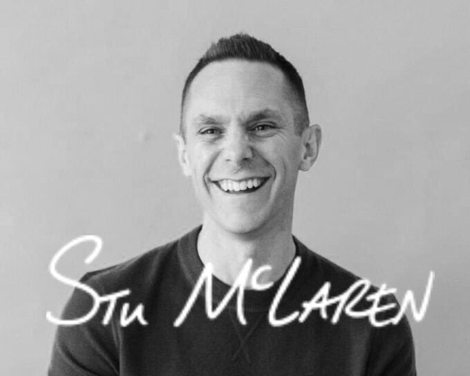 A black and white photo of a man smiling at the camera with the words 'Stu McLaren" over the top.