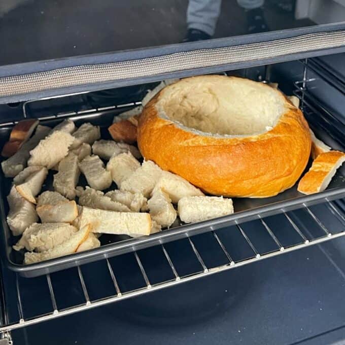 a cob loaf with pieces of bread on a tray in the oven.