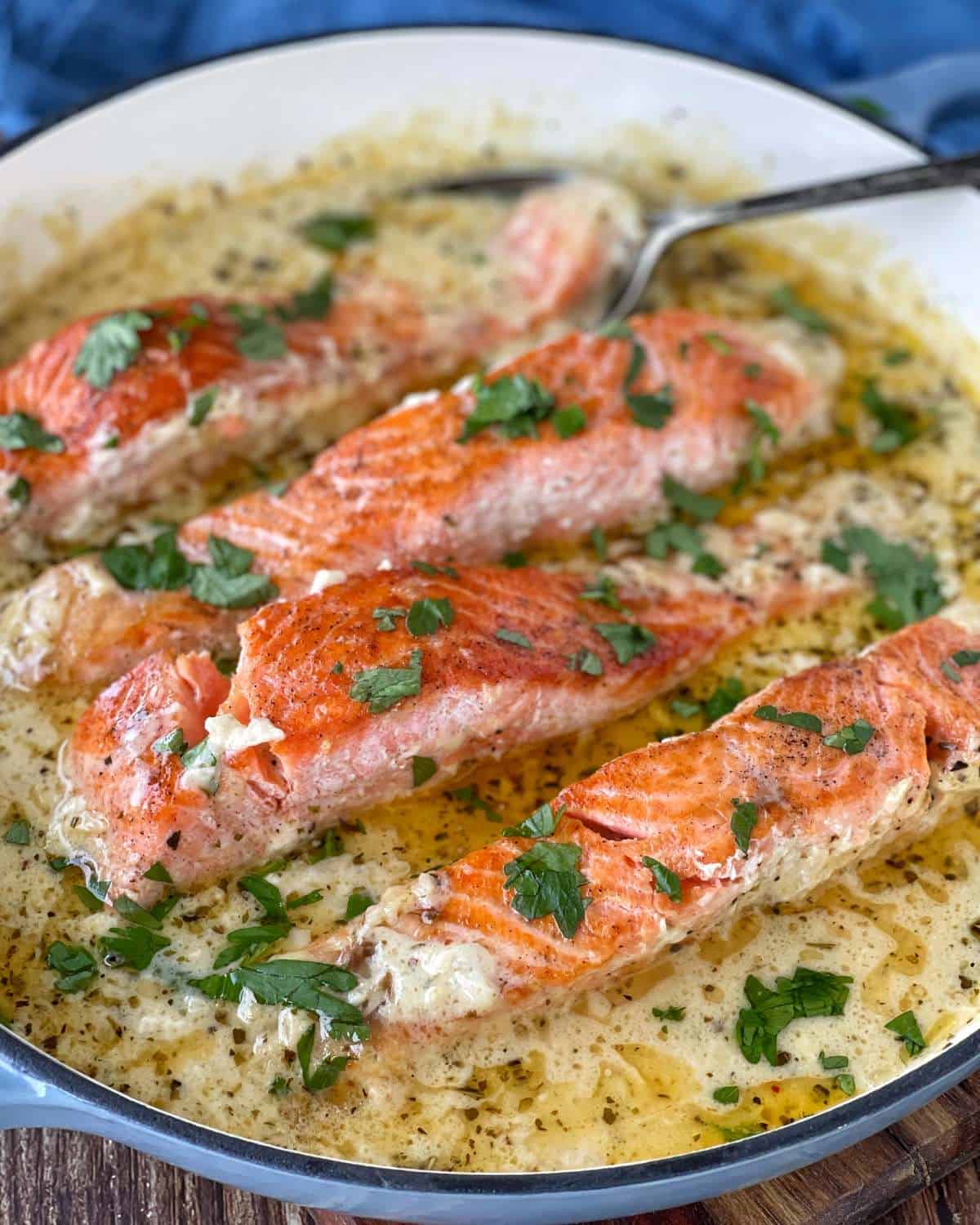 A close up shot of cooked Creamy Salmon fillets in a round ceramic dish.